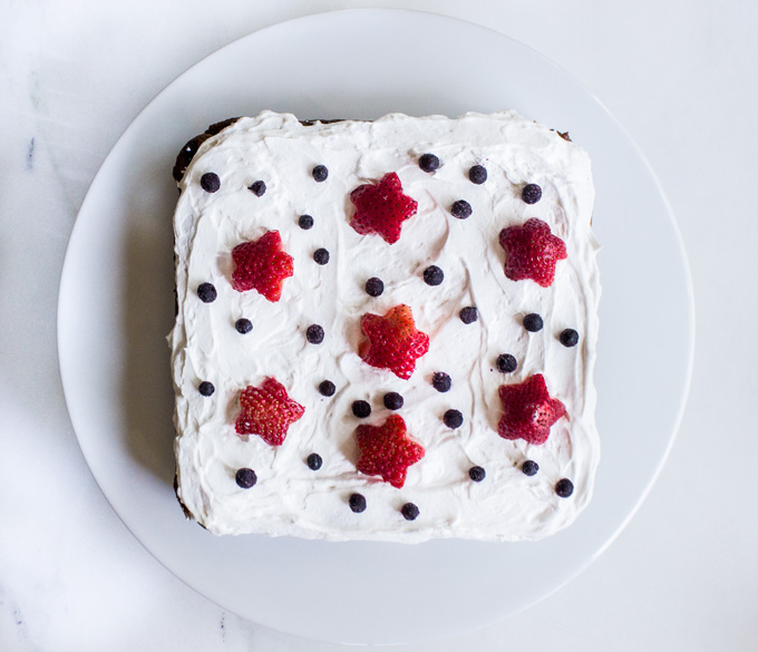 Overhead view of a Blueberry Snack Cake with strawberry and blueberry toppings, placed in a round white plate